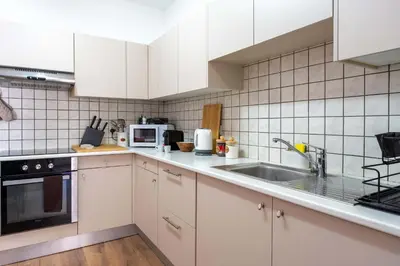 a kitchen with white cabinets and a sink at Stylish 2BR Apartment with Rooftop Pool in Mackenzie in Larnaka