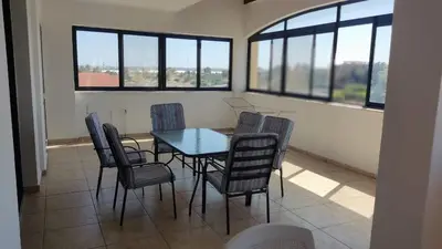 a dining room with a table and chairs and windows at Poseidon 502 penthouse in Larnaka
