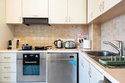 a kitchen with white cabinets and a stainless steel dishwasher at Mystique 1-Bedroom Apartment in Larnaka
