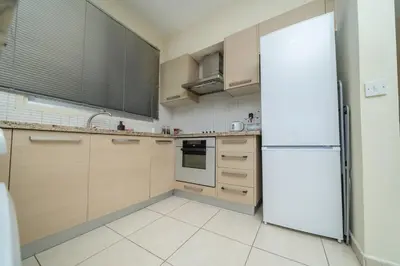 a kitchen with wooden cabinets and a white refrigerator at Modern 2 bedroom flat in Engomi in Strovolos