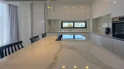 a large white kitchen with a glass table in it at Aqua Beachfront Villas - Villa 1 in Ayia Napa