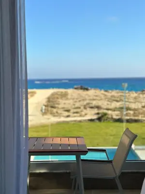 a table and a chair on a balcony with the ocean at Aqua Beachfront Villas - Villa 2 in Ayia Napa