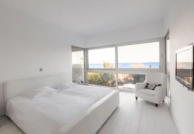 a white bedroom with a large bed and a chair at Katerina House in Pervolia
