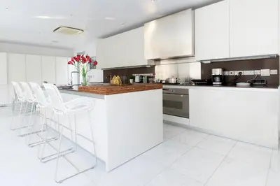 a kitchen with white cabinets and white stools at Katerina House in Pervolia