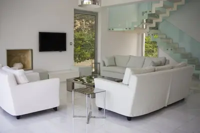 a living room with white furniture and a staircase at Katerina House in Pervolia