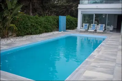 a blue swimming pool with chairs and a house at Katerina House in Pervolia