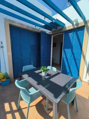 a table and chairs on a patio with blue shutters at Possidon Beach Getaway in Meneou