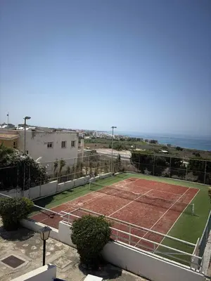 a tennis court with the ocean in the background at Ikaria Village, Maisonette Sea 10 in Aglantzia