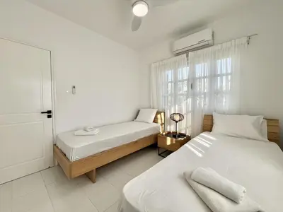 a white bedroom with two beds and a window at STAY Cavo Bay Villa in Protaras