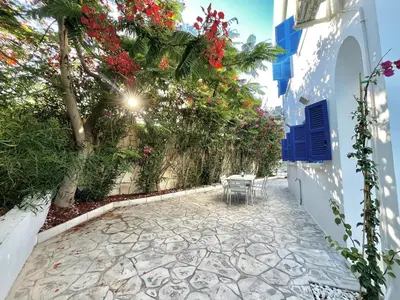 a patio with tables and flowers on a building at STAY Cavo Bay Villa in Protaras