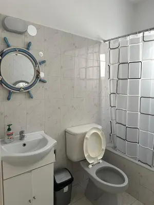 a white bathroom with a toilet and a sink at Sunny house in Larnaka