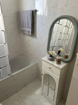 a white bathroom with a tub and a mirror at Sunny house in Larnaka