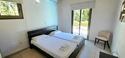 a bedroom with a bed and a chair and a window at Agia Thekla bungalow with pool in Ayia Napa