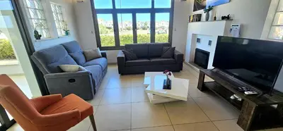 a living room with couches and a flat screen tv at Agia Thekla bungalow with pool in Ayia Napa