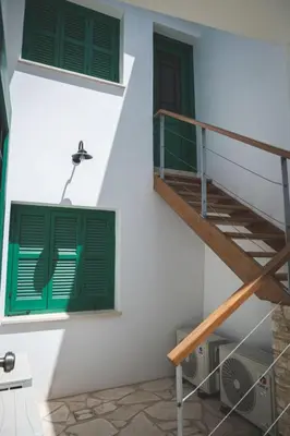 a building with green windows and a staircase at Elite luxury Suites in Omodos