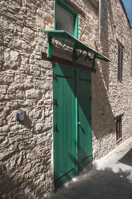 a green door on the side of a stone building at Elite luxury Suites in Omodos