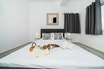 a bedroom with a large white bed with black curtains at Central 2 bedroom flat in Nicosia