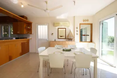 a kitchen and dining room with a white table and chairs at Frontline Sea-View Villa in Paralimni