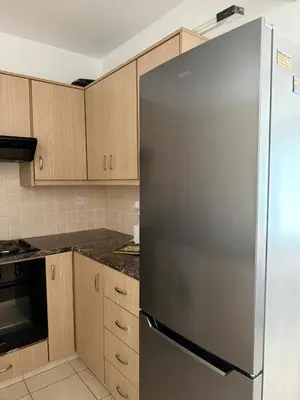 a stainless steel refrigerator in a kitchen with wooden cabinets at Serenity Apartment with Pool in Paralimni