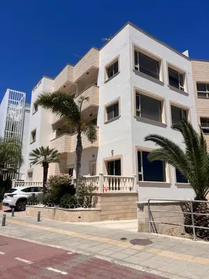 a white building with palm trees in front of it at Sandy Nest Studio in Larnaka