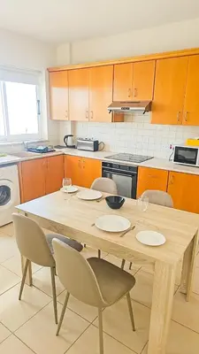 a kitchen with a wooden table with chairs and a table and a tableastery at The Poolside Escape Apartment in Larnaka