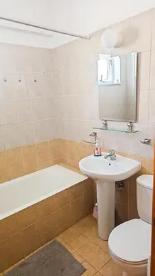 a bathroom with a sink and a tub and a toilet at The Poolside Escape Apartment in Larnaka