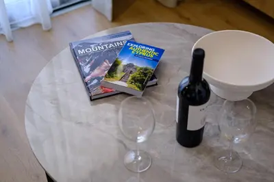 a table with wine glasses and a magazine and a wine bottle at Artemis 103 - Seaside Stories in Livadhia