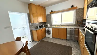 a kitchen with wooden cabinets and a table and a sink at Modern 3BDR_Top Floor_Lux_Suite_Balcony in Limassol