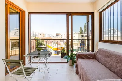 a balcony with a couch and a table and chairs at Market View Apartment - Near The Beach in Larnaka