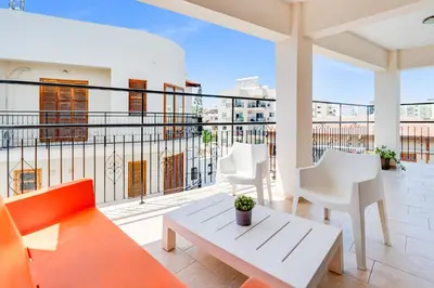 a balcony with white furniture and a view of a building at Market View Apartment - Near The Beach in Larnaka