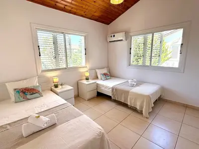 a bedroom with two beds and two windows at Elegant Beach Villa Moonstone II in Meneou