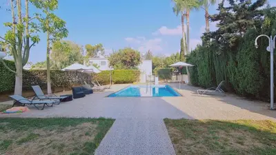 a swimming pool in a yard with chairs and umbrellas at Nissi 87 Apartment - Luxcyservices in Ayia Napa