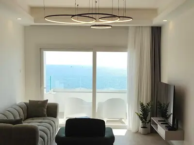 a living room with a couch and a large window at Joyscape beachfront residence in Larnaka