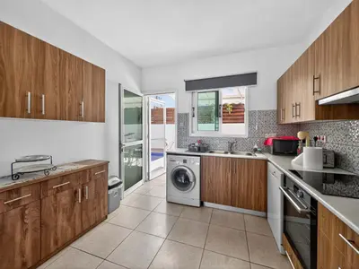 a kitchen with wooden cabinets and a washer and dryer at Villa Rena - 3BR Retreat near Kalamies Beach in Paralimni