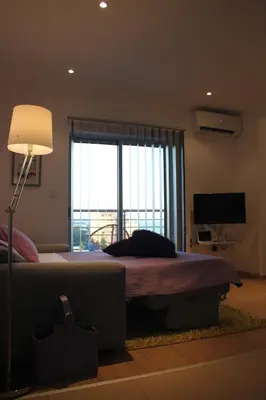 a bedroom with a bed with a lamp and a window at Eden Beach Apartment 611 in Limassol