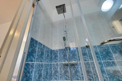 a shower in a bathroom with blue tiles at Penthouse Central Larnaca The 'Veranda' Elena Court in Larnaka