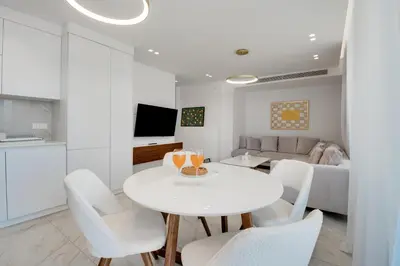 a white living room with a white table and chairs at Oniro Suites Makenzy in Larnaka