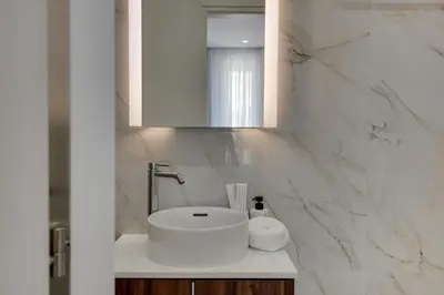a white bathroom with a sink and a mirror at Oniro Suites Makenzy in Larnaka