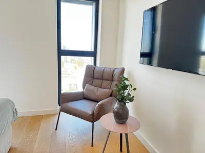 a brown chair in a living room with a vase on a table at SkyHigh Park View Living in Nicosia