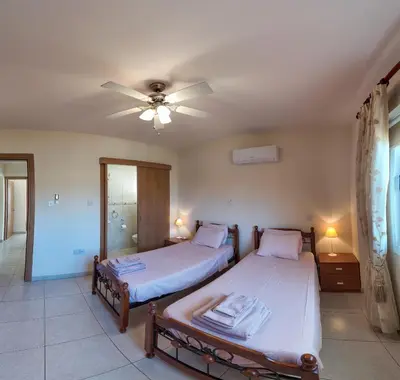 two beds in a room with a ceiling fan at Golden Sands No10 in Ayia Napa
