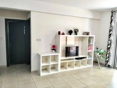 a living room with a tv and a white shelf at Regina by the Sea in Limassol
