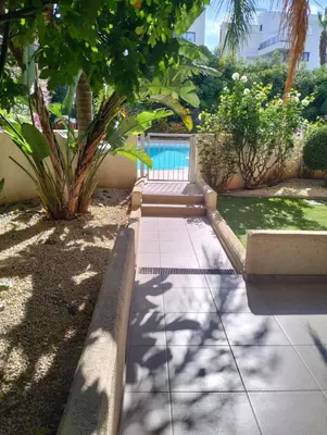 a garden with a swimming pool and a sidewalk at Regina by the Sea in Limassol