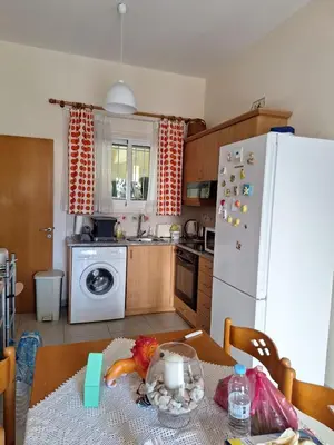 a kitchen with a table and a white refrigerator at ισόγειο διαμέρισμα με αυλή στην περιοχή Κάππαρη κατάλληλο για οικογενεια in Paralimni