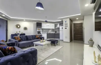 a living room with blue couches and a kitchen at Avrasya city in Ayios Dhometios