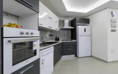a kitchen with white appliances and gray cabinets at Avrasya city in Ayios Dhometios