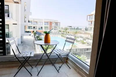 a table and chairs on a balcony with a view of a pool at Cosmos Residence C102 in Paralimni