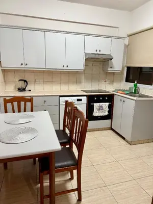 a kitchen with white cabinets and a table and chairs at Alison rooms in center in Larnaka