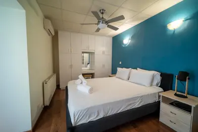 a bedroom with a large white bed with a blue wall at Casa Piedra, Hidden Gem, Jacuzzi, BBQ, Patio in Monagroulli in Monagrulli
