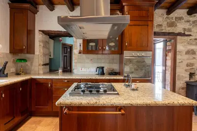 a kitchen with wooden cabinets and a stove top oven at Casa Piedra, Hidden Gem, Jacuzzi, BBQ, Patio in Monagroulli in Monagrulli