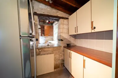 a small kitchen with white cabinets and a refrigerator at Casa Piedra, Hidden Gem, Jacuzzi, BBQ, Patio in Monagroulli in Monagrulli